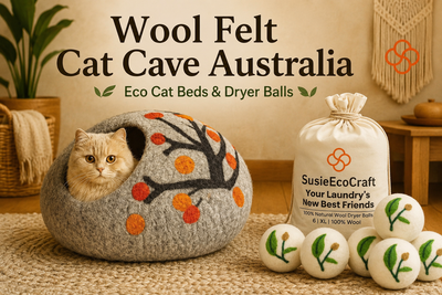 Wool felt cat cave and dryer balls with SusieEcoCraft branding on a wooden floor.